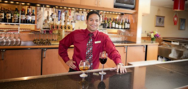 Bartender stands behind a glass of wine and a highball of scotch at the Westmark Fairbanks Hotel and Conference Center